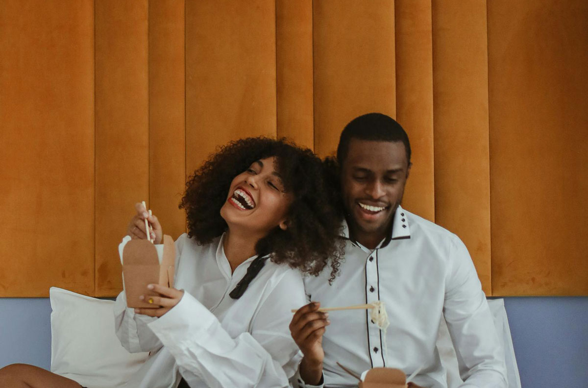 Young black couple smiling and eating together